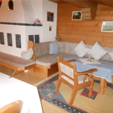 A cozy living area with wood paneling and a seating corner. A table with a blue tablecloth and inviting cushions creates a warm atmosphere.