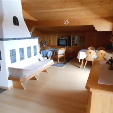 A cozy living space with wooden paneling and a warm atmosphere. The room features a fireplace, a dining table, and comfortable seating.