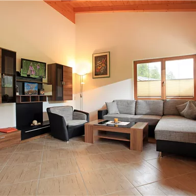 A modern living room with comfortable furniture and large windows. A cozy atmosphere is created by the wood paneling and the decorative elements.