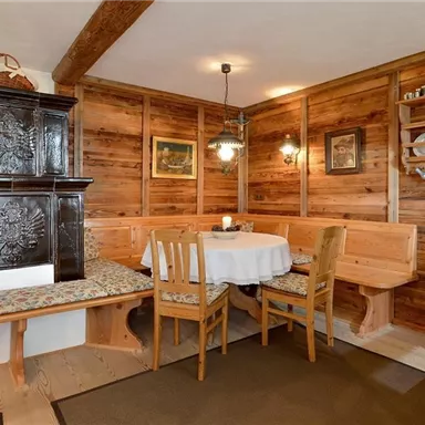 A cozy room with wooden walls and a traditional stove. A round table with chairs invites you to linger.
