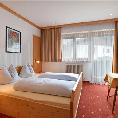 A cozy bedroom with two single beds. The room is bright and friendly with a table and chairs.
