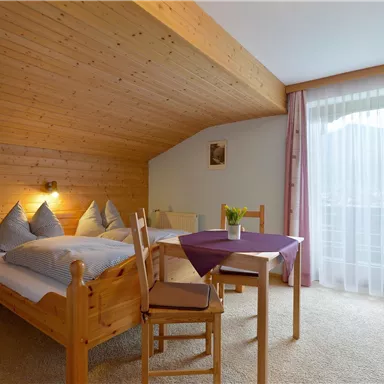 Ein gemütliches Schlafzimmer mit Holzverkleidung und zwei Betten. Ein kleiner Tisch neben dem Fenster mit Blick nach draußen.