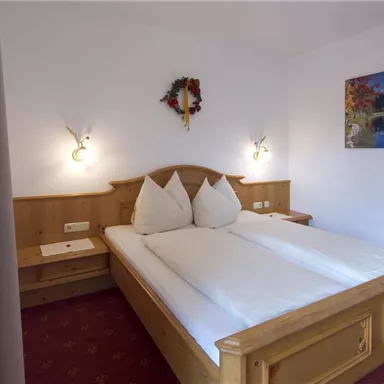 Ein gemütliches Schlafzimmer mit zwei Einzelbetten und Holzverkleidung. An der Wand hängt ein Bild mit einer Landschaft, und das Zimmer ist mit warmen Farbtönen dekoriert.