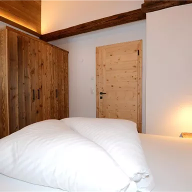A cozy bedroom with a large bed and wooden cabinets. The warm colors create a relaxed atmosphere.