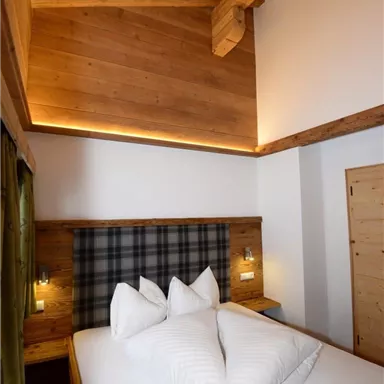 A cozy bedroom with a wooden bed and modern lighting elements. The decor exudes a warm and inviting character.