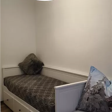 A cozy room with a single bed and an additional seating area. The walls are light, and the decoration is simple and modern.