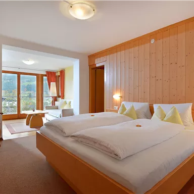 A cozy room with a double bed and warm wooden walls. The window offers a view of the mountains and plenty of natural light.