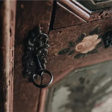 An old piece of furniture with floral embellishments and a key. The wooden surface shows patina and details from the past.
