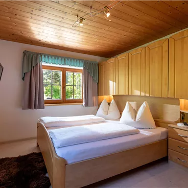 Ein gemütliches Schlafzimmer mit zwei Einzelbetten und Holzschränken. Tageslicht fällt durch das Fenster und sorgt für eine einladende Atmosphäre.