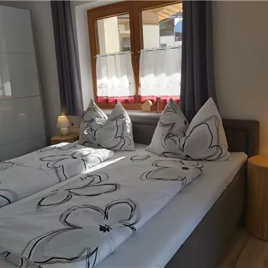 An inviting bedroom with two single beds. The windows let in bright light and the decor is modern and cozy.