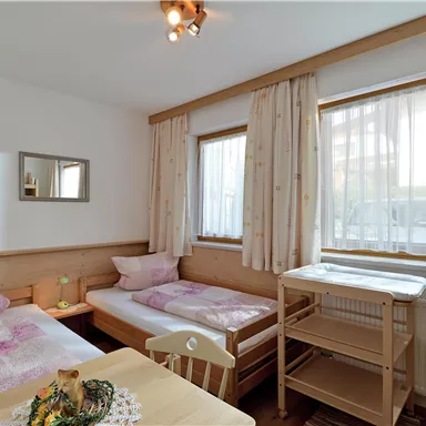A cozy room with two single beds and large windows. The bright colors create an inviting atmosphere.