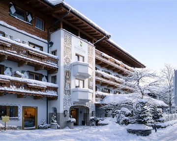 Ein charmantes Hotel im Winter mit schneebedeckten Balkonen und dekorativen Details. Die Umgebung ist ruhig und idyllisch, perfekt für einen entspannten Aufenthalt.