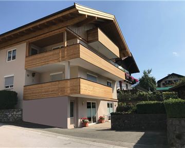 Ein modernes Haus mit Holzverkleidung und mehreren Balkonen. Es liegt in einer ruhigen Umgebung mit grünem Garten.