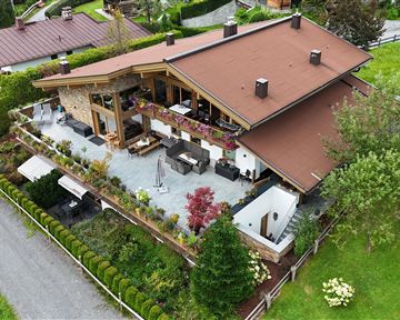 A beautiful house with a large garden and a terrace. The surroundings are green and well-maintained.