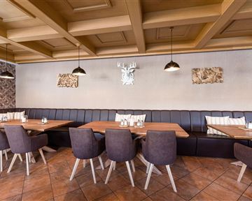 A modern restaurant with wooden tables and elegant chairs. The walls are tastefully decorated and there are cozy seating areas.