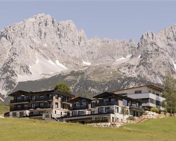 Ein modernes Gebäude in einer hügeligen Landschaft, umgeben von majestätischen Bergen. Die klare Luft und die beeindruckende Natur schaffen eine ruhige Atmosphäre.