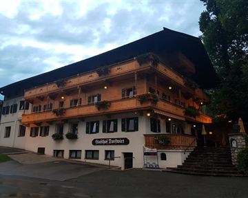 Ein traditionelles Gasthaus mit mehreren Etagen und Balkon. Die Fassade ist aus Holz und mit Blumen geschmückt.