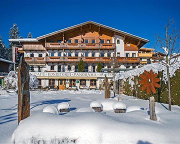Ein charmantes Gebäude im Alpenstil, umgeben von schneebedeckten Landschaften. Der klare blaue Himmel ergänzt die winterliche Szenerie.