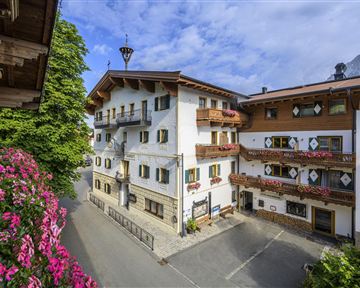 Ein malerisches Dorf mit traditionellen Gebäuden und blühenden Blumen. Die klare Luft und die Aussicht auf die Berge schaffen eine einladende Atmosphäre.