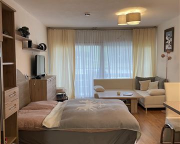 A bright and cozy room with a double bed and a seating area. Large windows provide plenty of daylight.