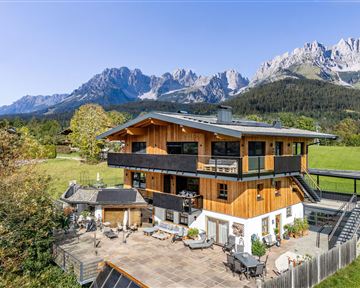 A modern wooden house surrounded by beautiful scenery and majestic mountains. The terrace offers a magnificent view of nature.