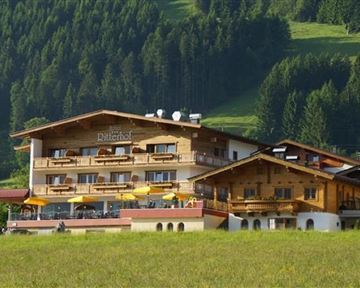 A charming hotel in the mountains with a wooden facade and balconies. Surrounded by green forests and beautiful scenery.