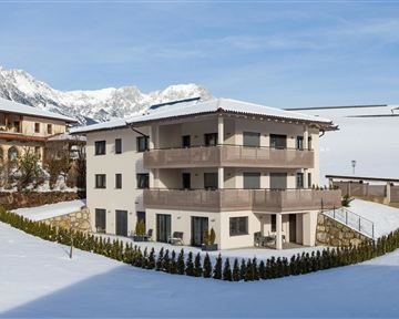 A modern house in the snow with a view of the mountains. The surroundings are quiet and idyllic.