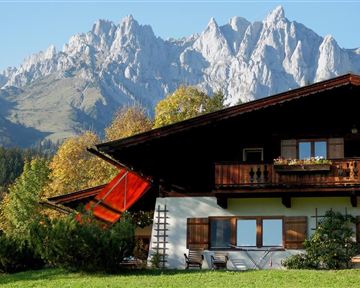 Ein malerisches Chalet vor imposanten Berggipfeln. Die Umgebung ist grün und einladend, ideal für einen Rückzugsort in der Natur.