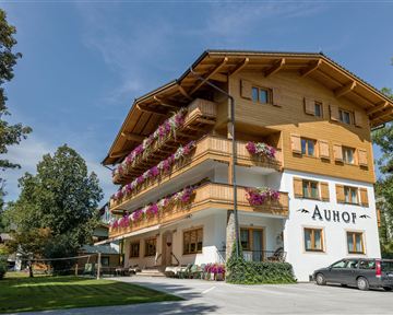 Ein charmantes Holzgebäude mit Balkonen und bunten Blumen. Umgeben von viel Grün in einer ruhigen Umgebung.